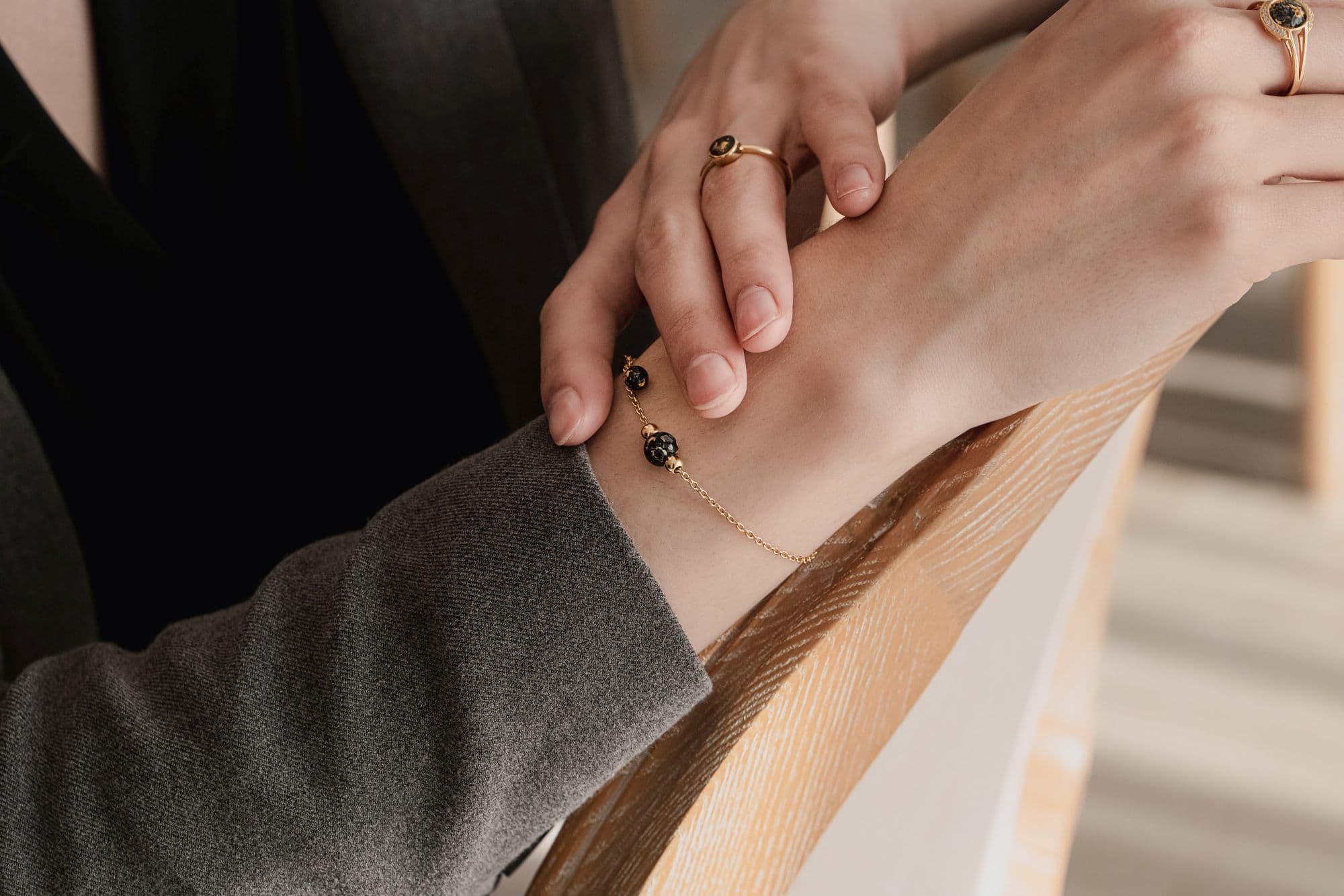 Goldfarbenes Armband mit schwarz gesprenkelten Perlen.