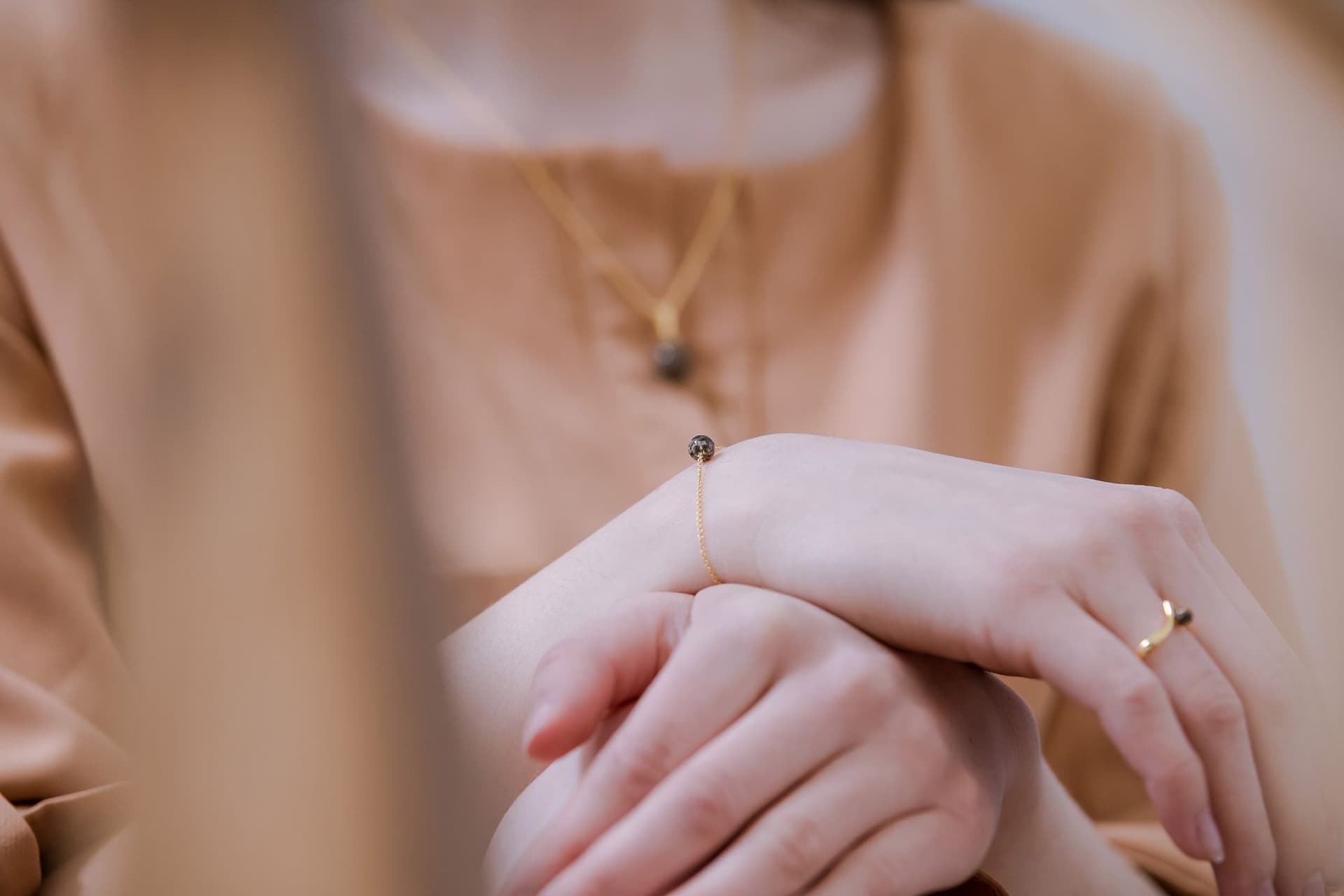 Gouden armband met een enkele donkere, gespikkelde parel.