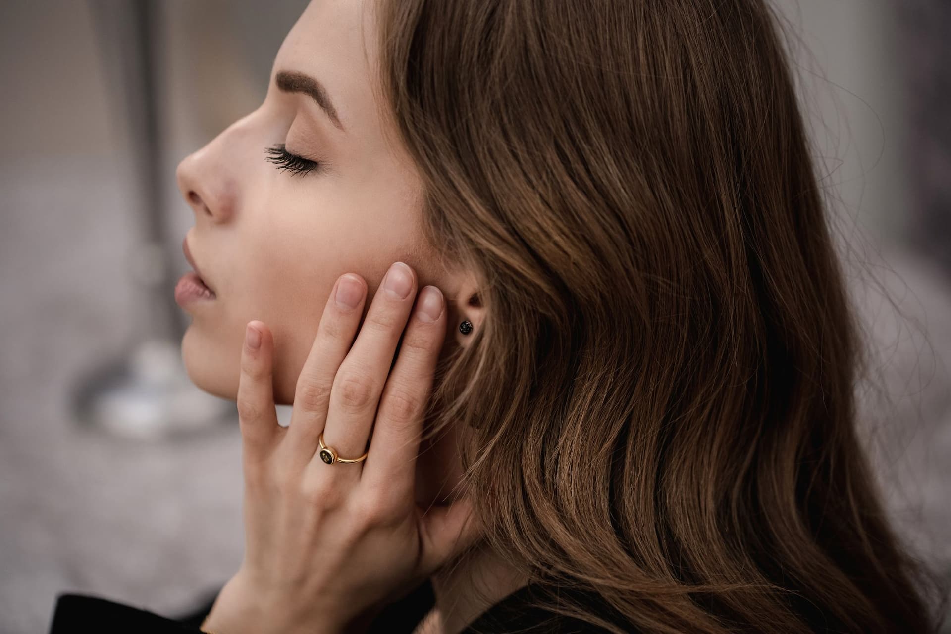 Gouden ring met een donkere, ronde steen en een bijpassende zwarte oorknop.