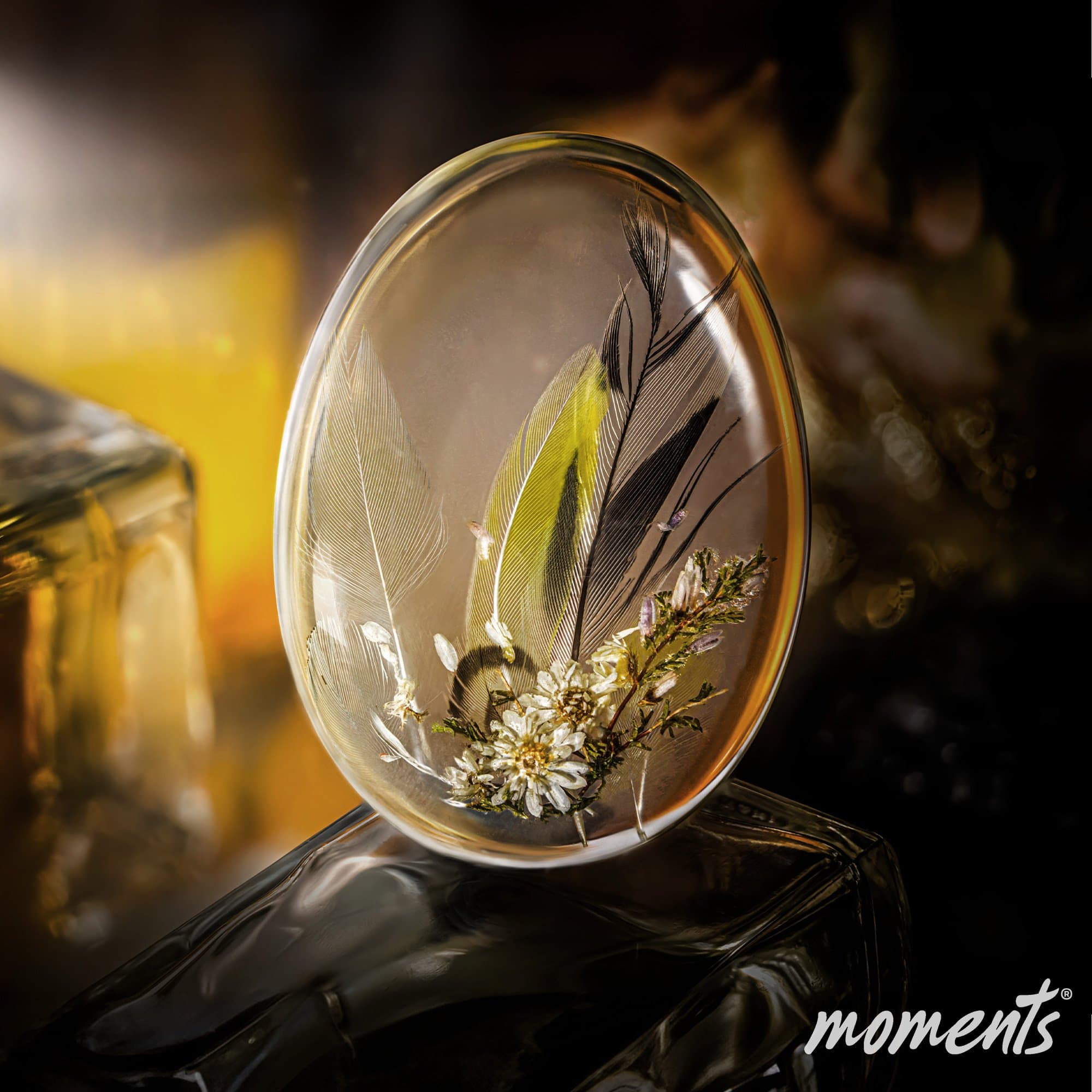 Ovaler Glasanhänger mit Federn, getrockneten Blumen und grünen Akzenten.