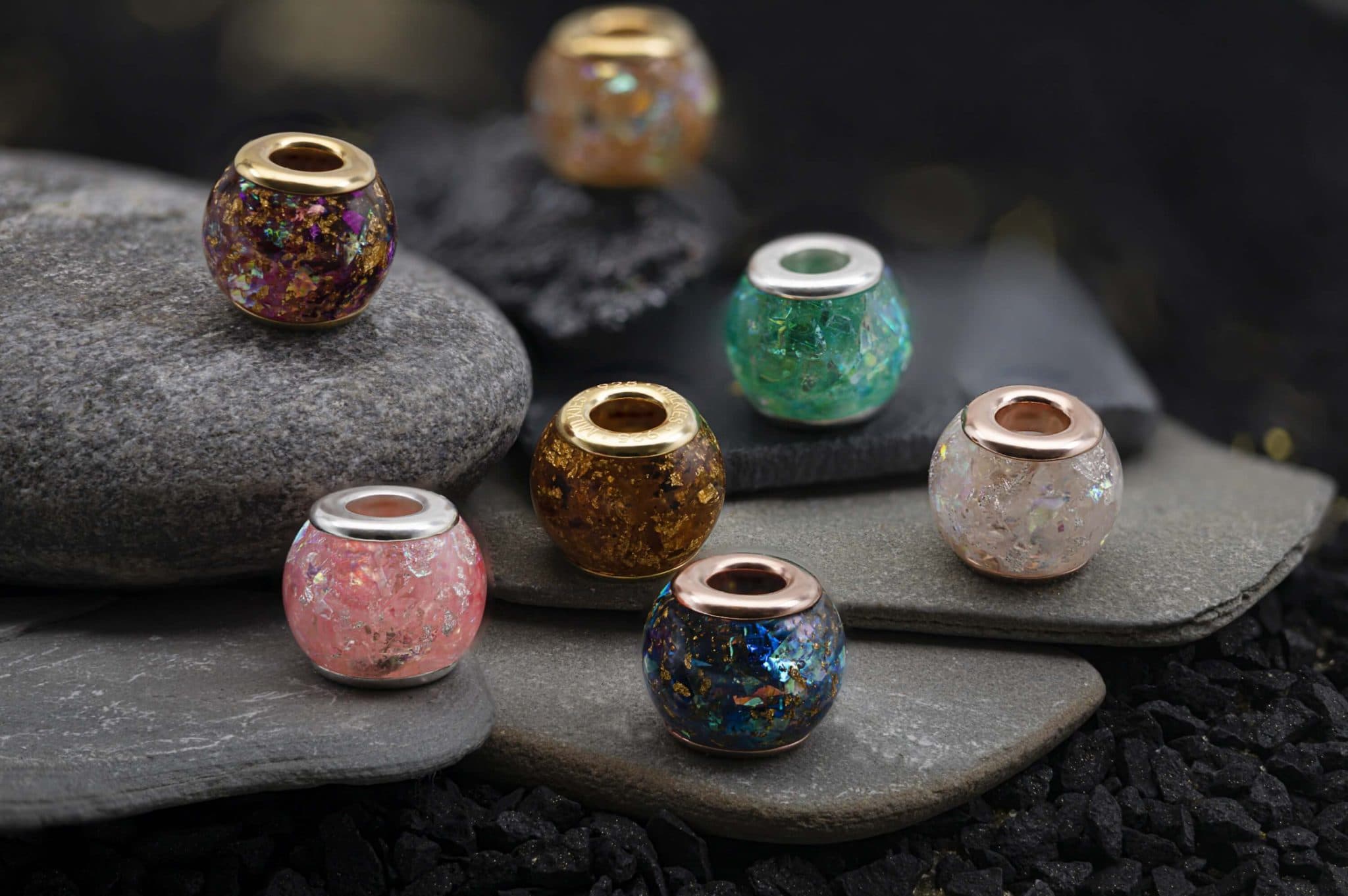 Runde Perlen mit eingeschlossenen schillernden Flocken und Metallfassungen in Gold, Silber oder Roségold.