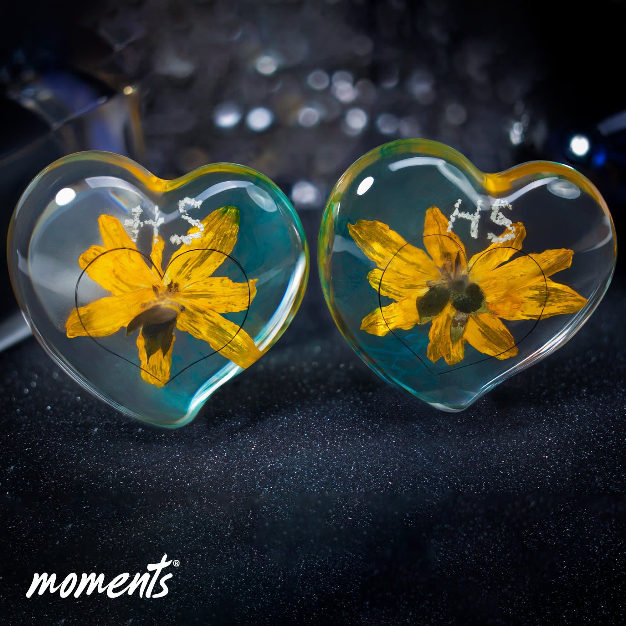 Klarer herzförmiger Schmuck aus Harz mit einer gelben Blüte und der weißen Inschrift HS.