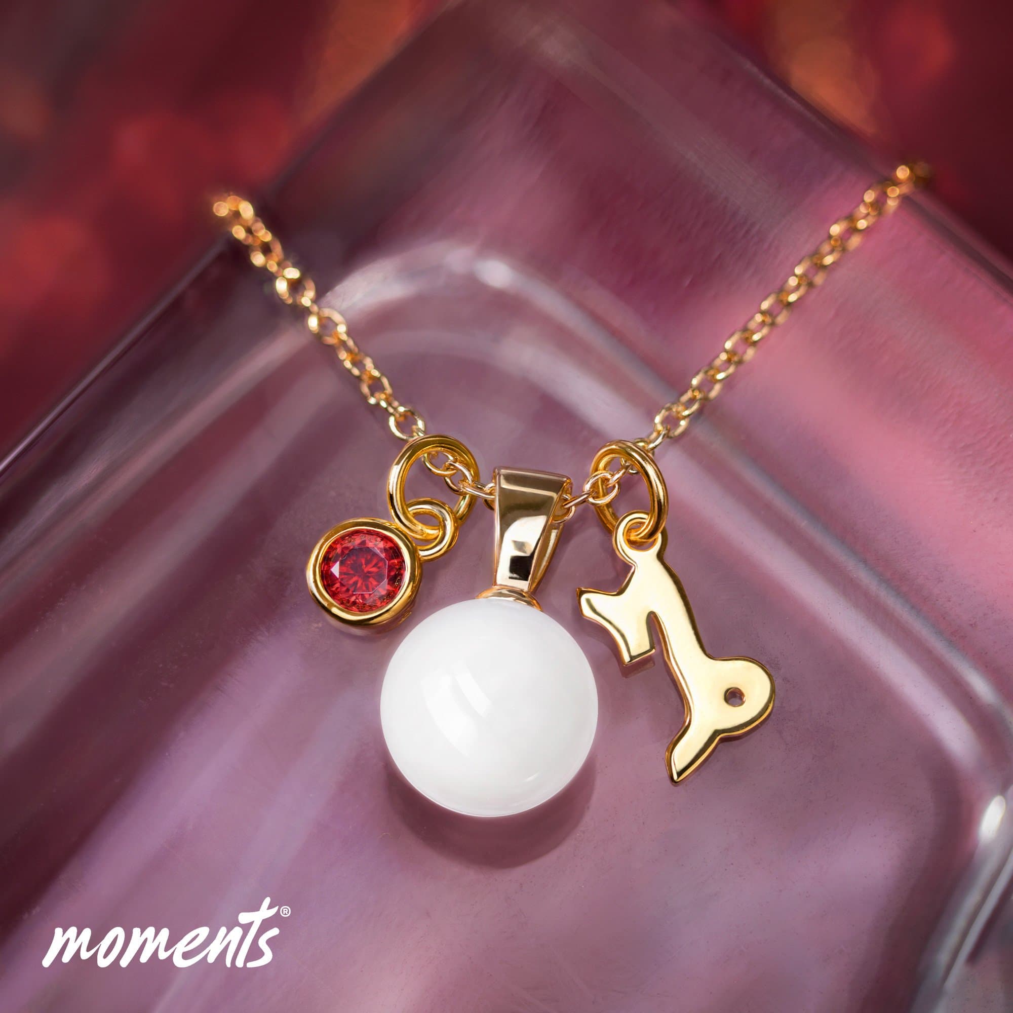 Goldene Gliederkette mit weißer Perle, rotem Edelstein und Steinbock-Sternzeichen-Charm.
