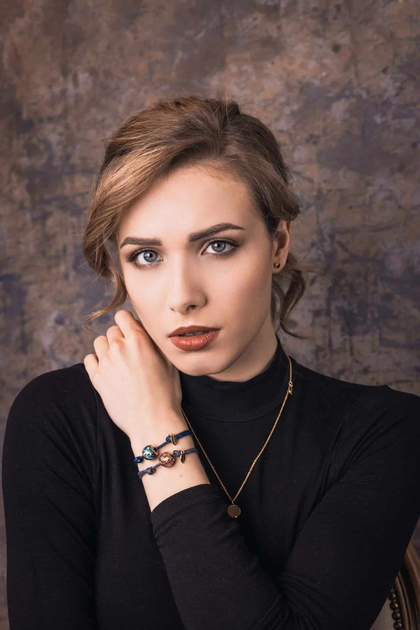 Zwei blaue Kordelarmbänder mit runden, bunten Glasanhängern und goldenen Akzenten.