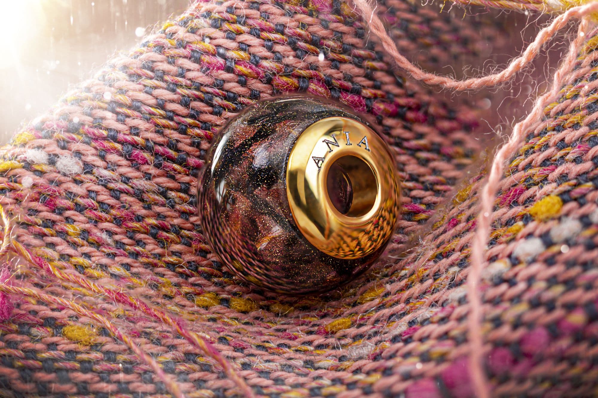 Runde Glasperle mit Goldflocken und einem goldfarbenen Einsatz, der mit "ANIA" graviert ist.