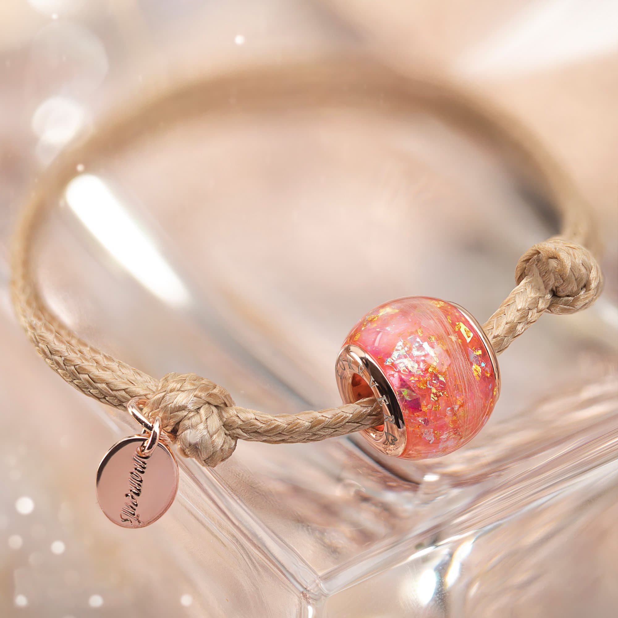Roségoldenes Charm-Armband mit einer rosa, mit Glitzer gefüllten Perle und einem runden Scheibenanhänger.