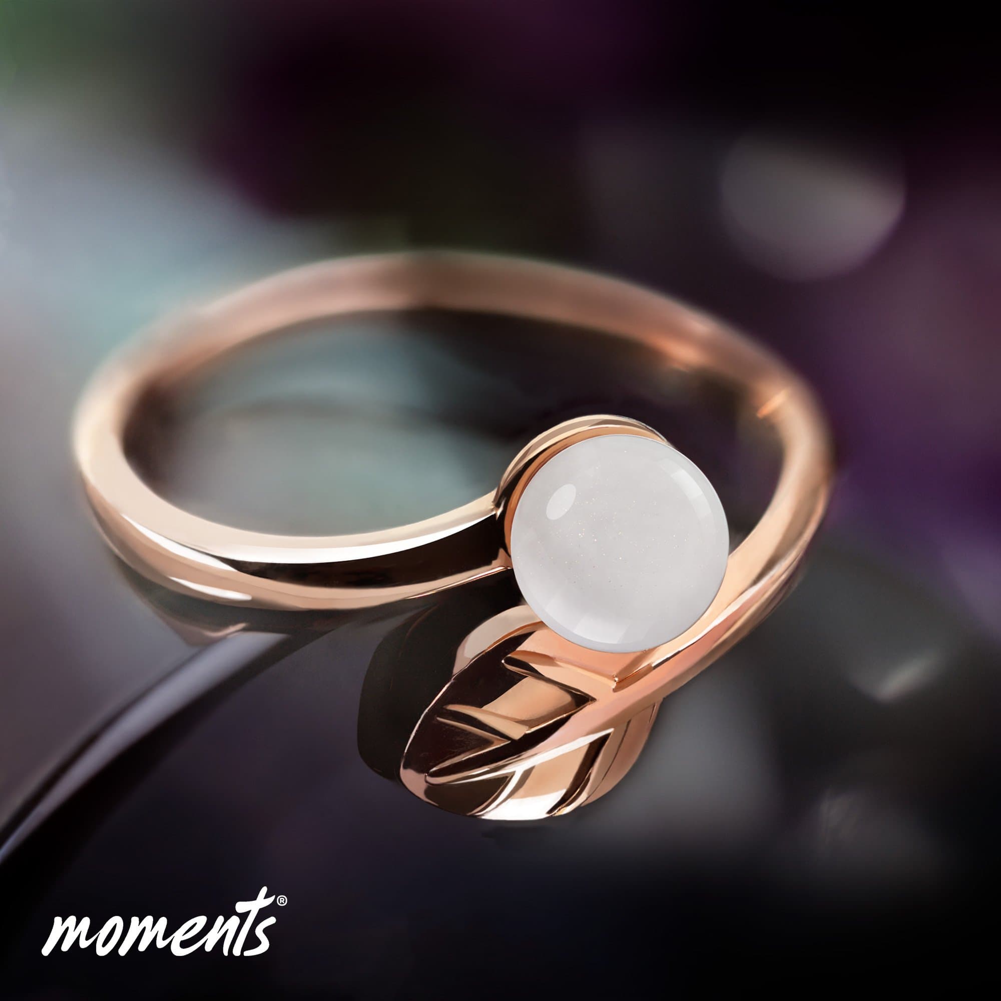 Roségoldring mit einem weißen, glitzergesprenkelten Cabochon und einem Blattdesign.