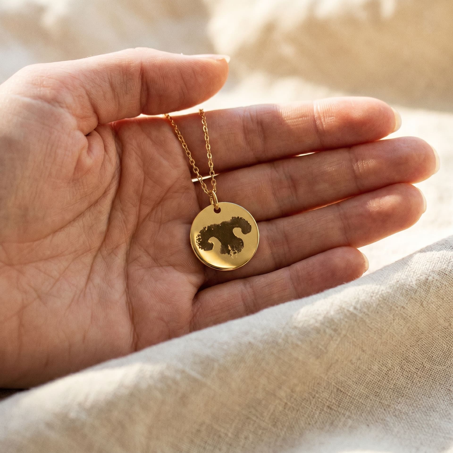 Luna Pendant with Pawprint - held in hand, second view
