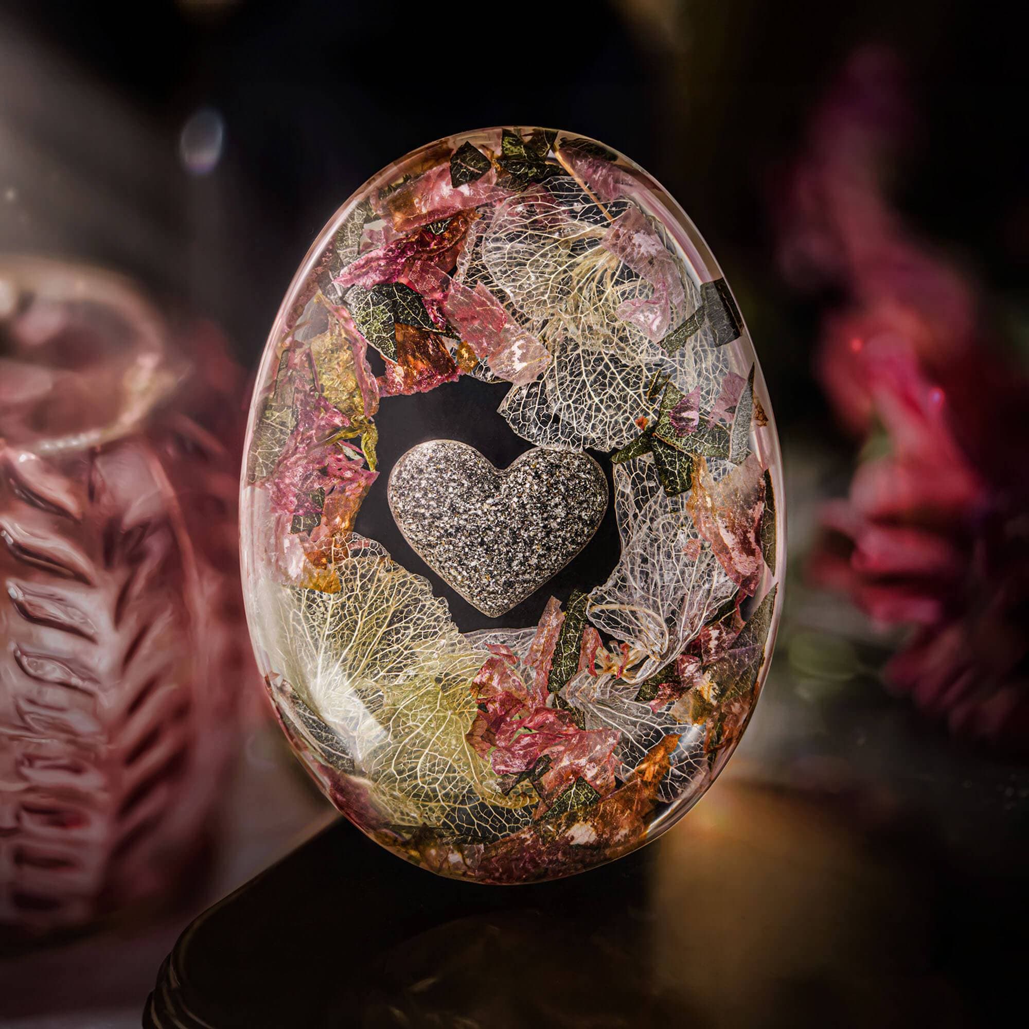 Eiförmiger Gedenkstein aus Harz mit eingebetteten getrockneten Blumen, Blättern und einem gesprenkelten grauen Herz.